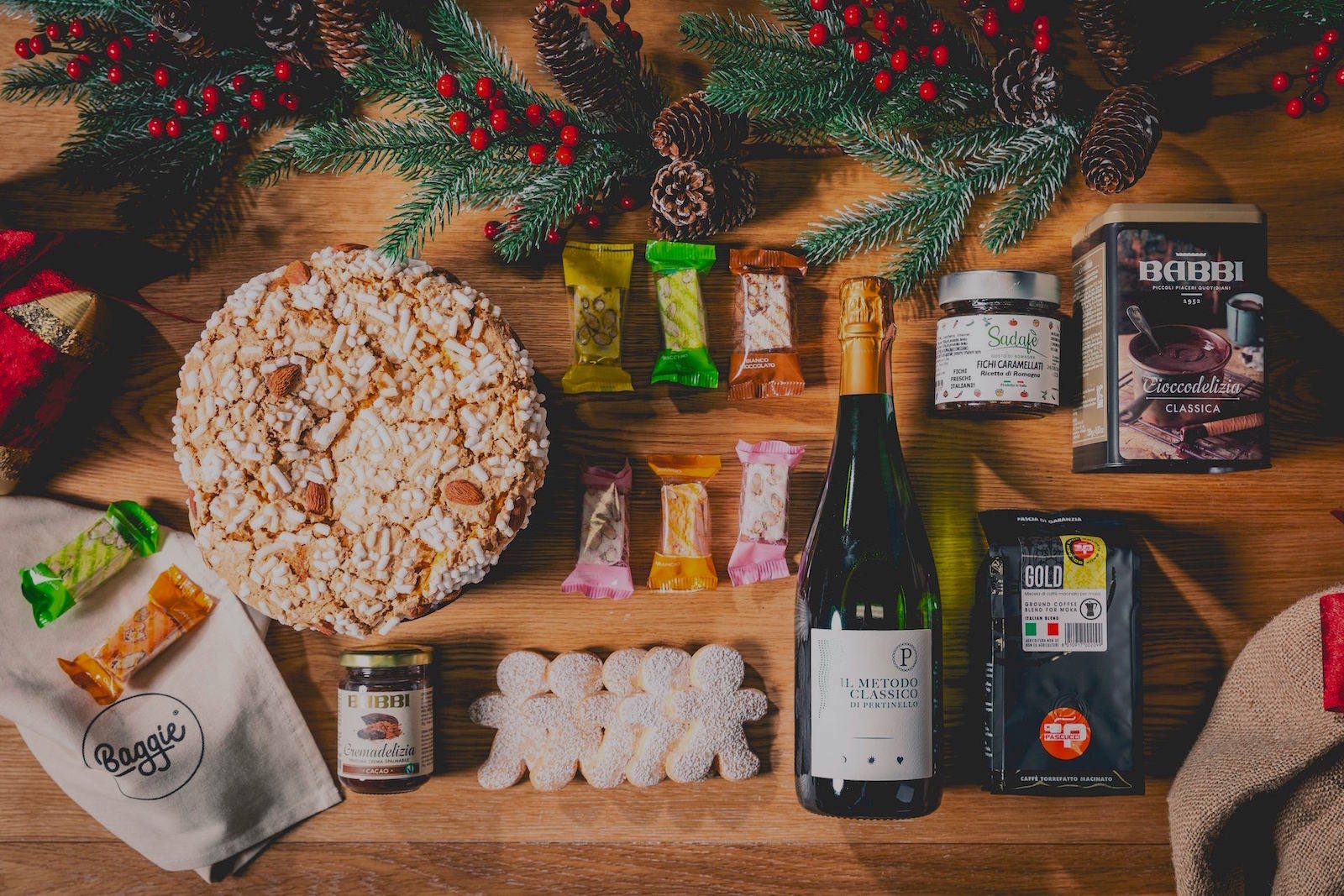 Panettone artigianale, biscotti a forma di omino, vino spumante metodo classico, crema spalmabile, torroncini, strofinaccio, caffè per moka, ciocolata calda in latta e fichi caramellati